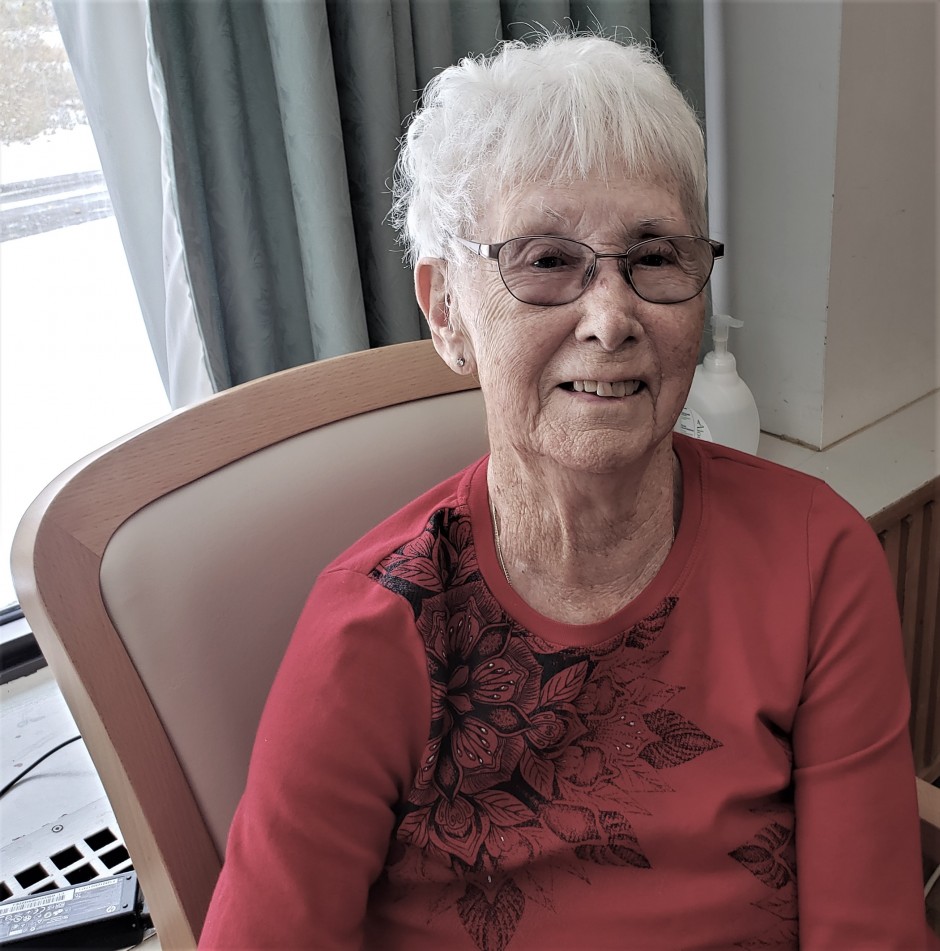 Elderly woman in red long sleeve and glasses smiling